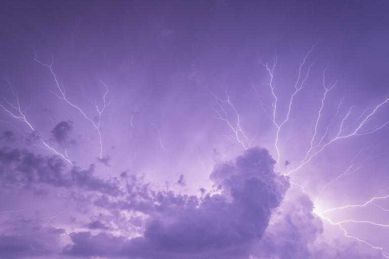 lightning over a purple sky with clouds.
