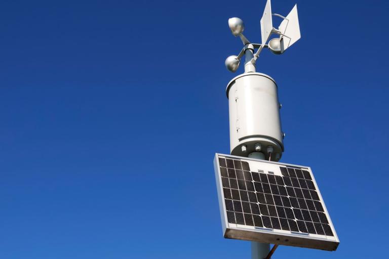 A solar powered weather station on a pole.