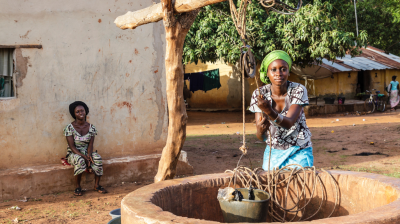 A woman is washing clothes in a well in a village.