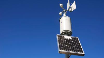 A solar powered weather station on a pole.