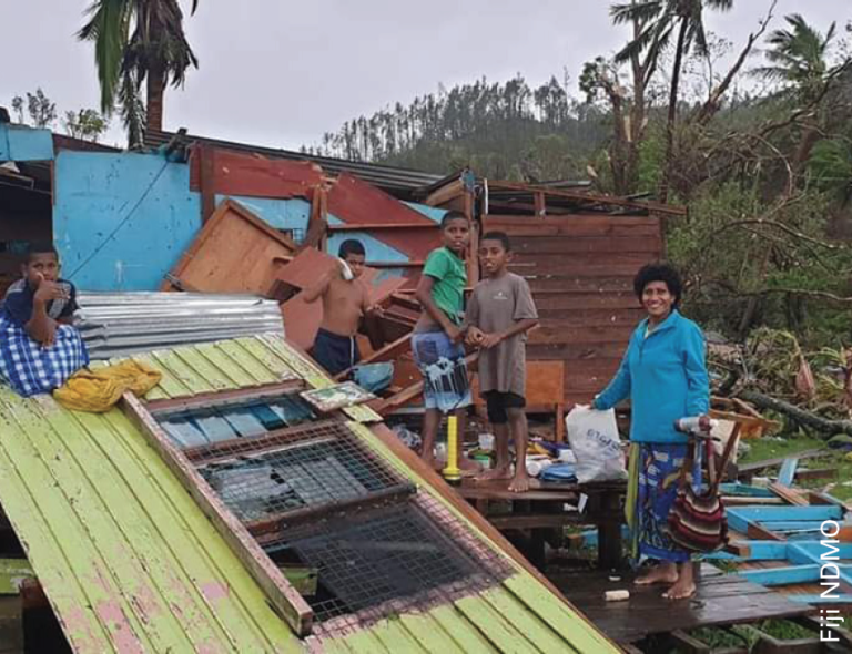 A group of people standing in front of a damaged house.